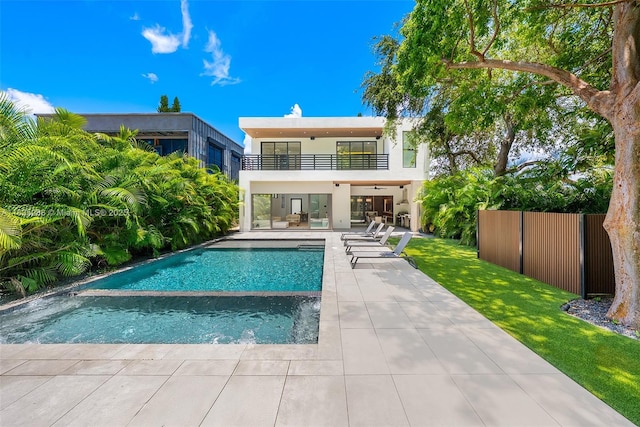260 NW 47th St, Miami, FL 33127 - rear view of property featuring a balcony, a patio area, stucco siding, and a pool with connected hot tub