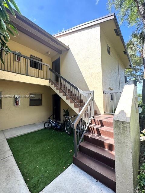3817 Cocoplum Cir Unit 3585, Coconut Creek, FL 33063 - doorway to property with stucco siding and a lawn