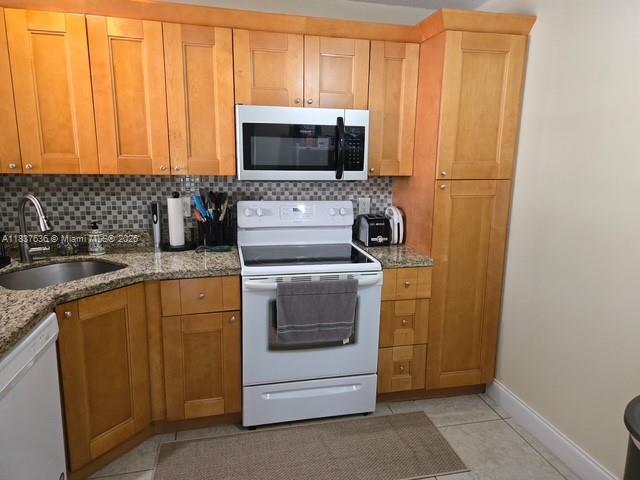 3817 Cocoplum Cir Unit 3585, Coconut Creek, FL 33063 - kitchen featuring white appliances, backsplash, light stone counters, and light tile patterned floors