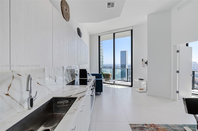 501 NE 31st St Unit 4007, Miami, FL 33137 - kitchen with a wall of windows, modern cabinets, light tile patterned floors, white cabinets, and black electric cooktop