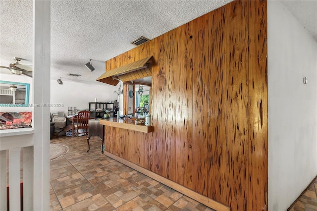 17041 Tarpon Way, Fort Myers, FL 33917 - kitchen featuring a textured ceiling, wood walls, and a ceiling fan