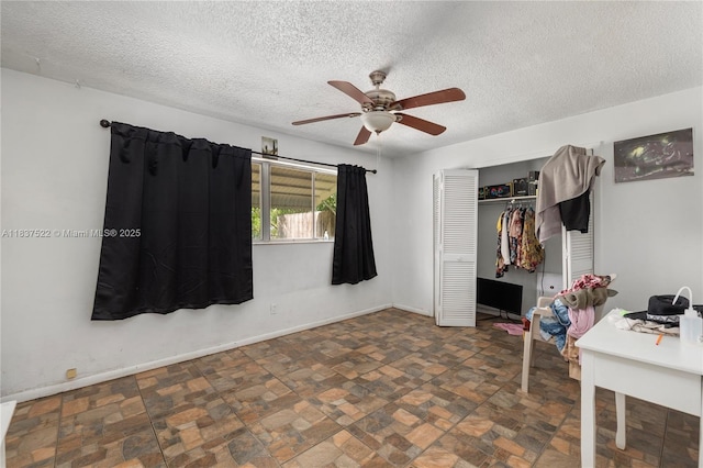 17041 Tarpon Way, Fort Myers, FL 33917 - bedroom featuring a textured ceiling, a closet, stone finish flooring, and a ceiling fan