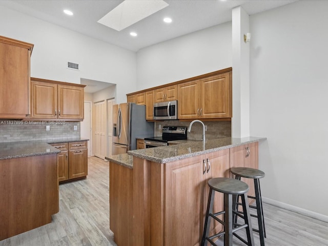 4024 Summer Chase Ct, Lake Worth, FL 33467 - kitchen featuring stainless steel appliances, a skylight, a kitchen breakfast bar, light wood finished floors, and a peninsula
