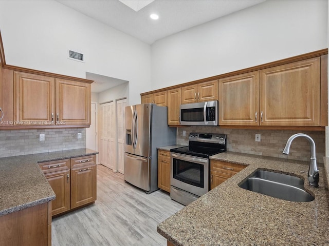 4024 Summer Chase Ct, Lake Worth, FL 33467 - kitchen featuring appliances with stainless steel finishes, a towering ceiling, light wood finished floors, dark stone countertops, and brown cabinetry