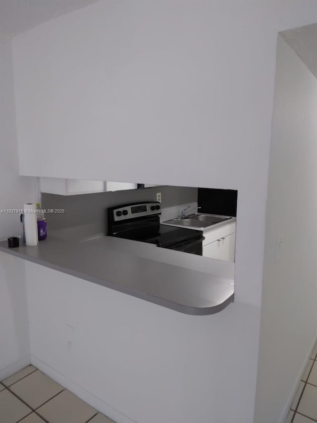 1305 W 46th St Unit 230, Hialeah, FL 33012 - kitchen with stainless steel electric stove, white cabinetry, light tile patterned floors, a peninsula, and modern cabinets
