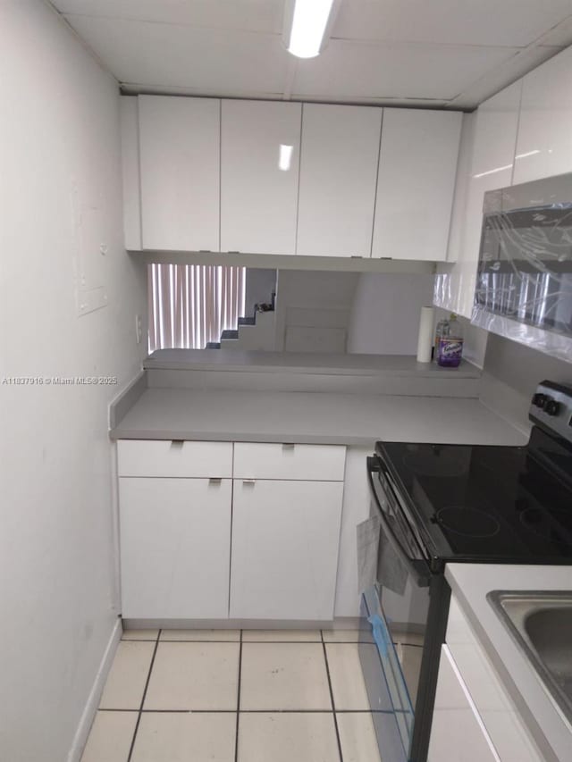 1305 W 46th St Unit 230, Hialeah, FL 33012 - kitchen with black electric range, white cabinets, and stainless steel microwave
