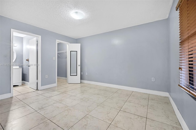 15560 SW 104th Ter Unit 611, Miami, FL 33196 - unfurnished bedroom with light marble finish flooring, a textured ceiling, a spacious closet, and ensuite bath