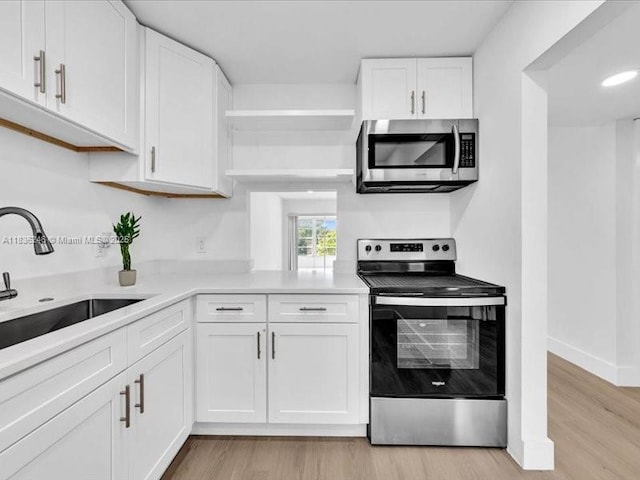 6000 NW 64th Ave Unit 303, Tamarac, FL 33319 - kitchen featuring stainless steel appliances, open shelves, light wood-style flooring, white cabinets, and light countertops