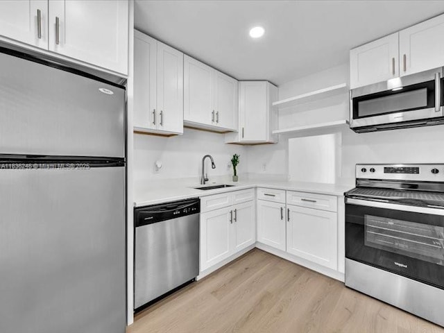 6000 NW 64th Ave Unit 303, Tamarac, FL 33319 - kitchen with appliances with stainless steel finishes, open shelves, light countertops, white cabinetry, and light wood-type flooring