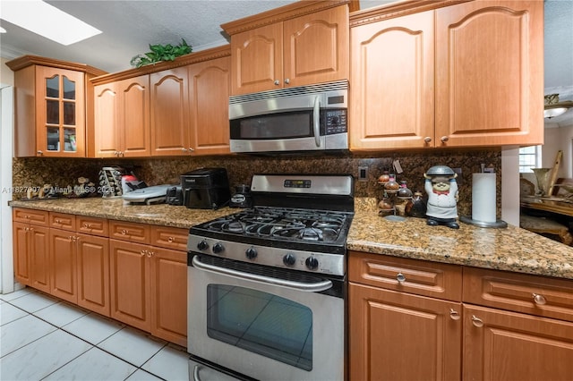 3631 SW 127th Ave, Miami, FL 33175 - kitchen featuring stainless steel appliances, a skylight, glass insert cabinets, tasteful backsplash, and light stone counters