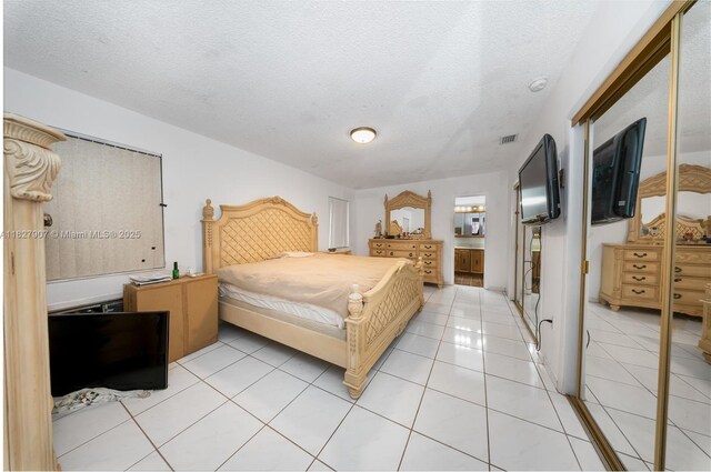 3631 SW 127th Ave, Miami, FL 33175 - bedroom with light tile patterned floors, a closet, a textured ceiling, and ensuite bathroom