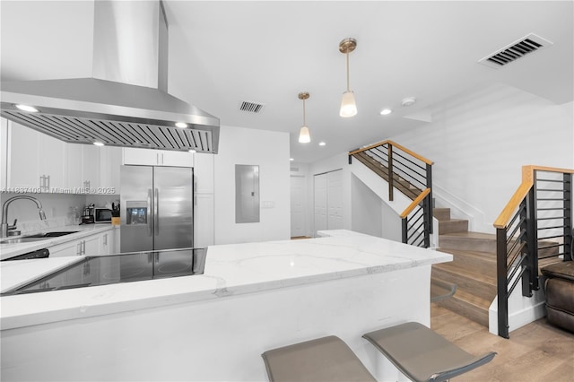 11128NW 17th Ave Unit 1-2, Miami, FL 33167 - kitchen featuring stainless steel fridge, wall chimney exhaust hood, white cabinetry, decorative light fixtures, and light stone counters