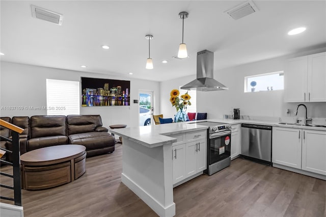 11128NW 17th Ave Unit 1-2, Miami, FL 33167 - kitchen featuring appliances with stainless steel finishes, island range hood, a peninsula, wood finished floors, and white cabinets