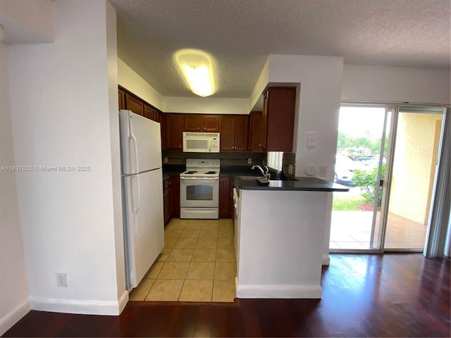 7640 Westwood Dr Unit 406, Tamarac, FL 33321 - kitchen with white appliances, dark countertops, a peninsula, a textured ceiling, and light wood-type flooring