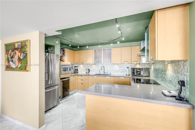 1623 Collins Ave Unit Ph1010, Miami Beach, FL 33139 - kitchen featuring stainless steel appliances, light marble finish floors, a peninsula, light brown cabinets, and tasteful backsplash