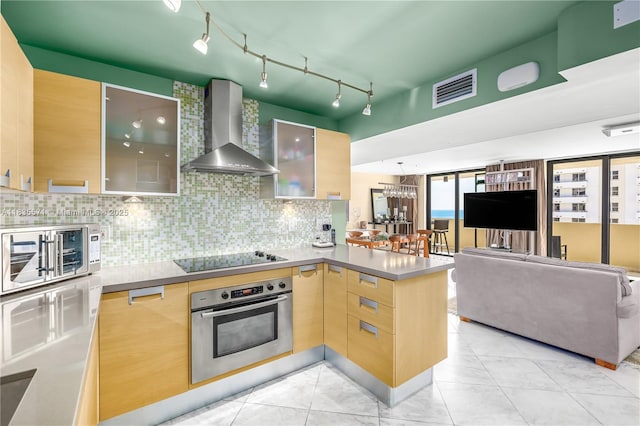 1623 Collins Ave Unit Ph1010, Miami Beach, FL 33139 - kitchen featuring stainless steel oven, wall chimney range hood, black electric cooktop, a peninsula, and glass insert cabinets