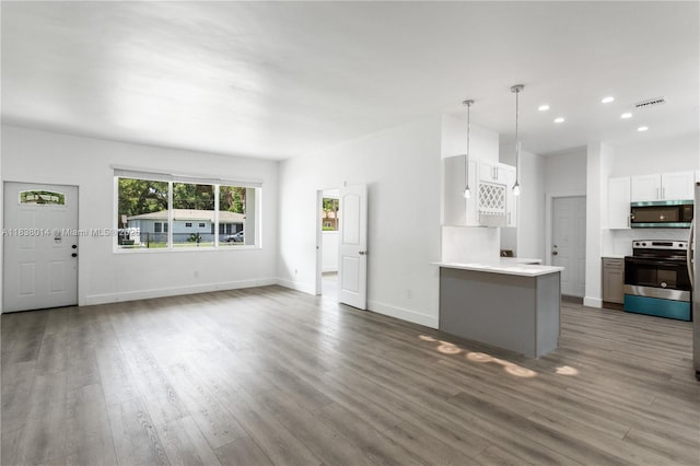 775 NE 145th St, North Miami, FL 33161 - kitchen with appliances with stainless steel finishes, wood finished floors, light countertops, white cabinetry, and recessed lighting