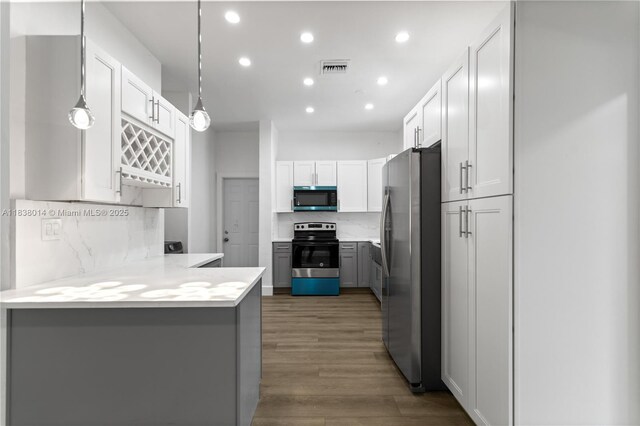 775 NE 145th St, North Miami, FL 33161 - kitchen with stainless steel appliances, a peninsula, recessed lighting, light countertops, and wood finished floors