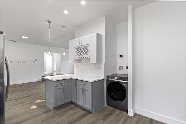 775 NE 145th St, North Miami, FL 33161 - kitchen with washer / dryer, gray cabinets, a peninsula, wood finished floors, and light countertops