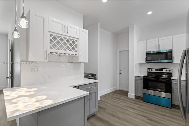775 NE 145th St, North Miami, FL 33161 - kitchen with stainless steel appliances, decorative backsplash, light wood-style floors, white cabinets, and recessed lighting