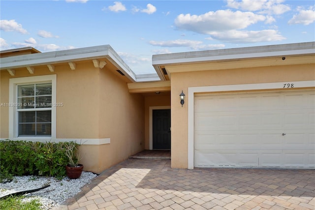 798 Quartz Ter, Palm Beach, FL 33413 - view of exterior entry featuring stucco siding, a garage, and driveway