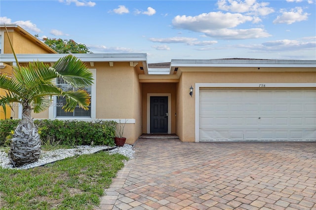 798 Quartz Ter, Palm Beach, FL 33413 - view of front of property featuring stucco siding, decorative driveway, and a garage