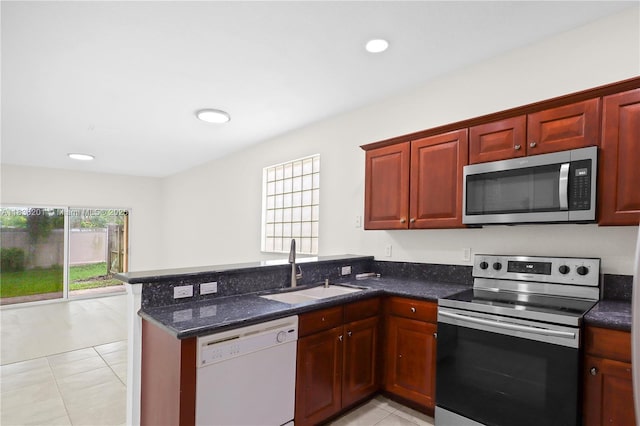 798 Quartz Ter, Palm Beach, FL 33413 - kitchen with appliances with stainless steel finishes, a peninsula, light tile patterned floors, dark stone counters, and reddish brown cabinets