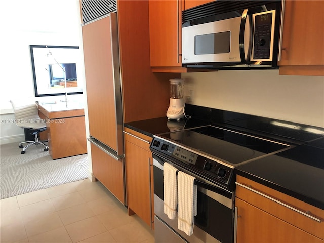 1435 Brickell Ave Unit 3106, Miami, FL 33131 - kitchen featuring stainless steel microwave, electric range oven, paneled refrigerator, dark countertops, and brown cabinets