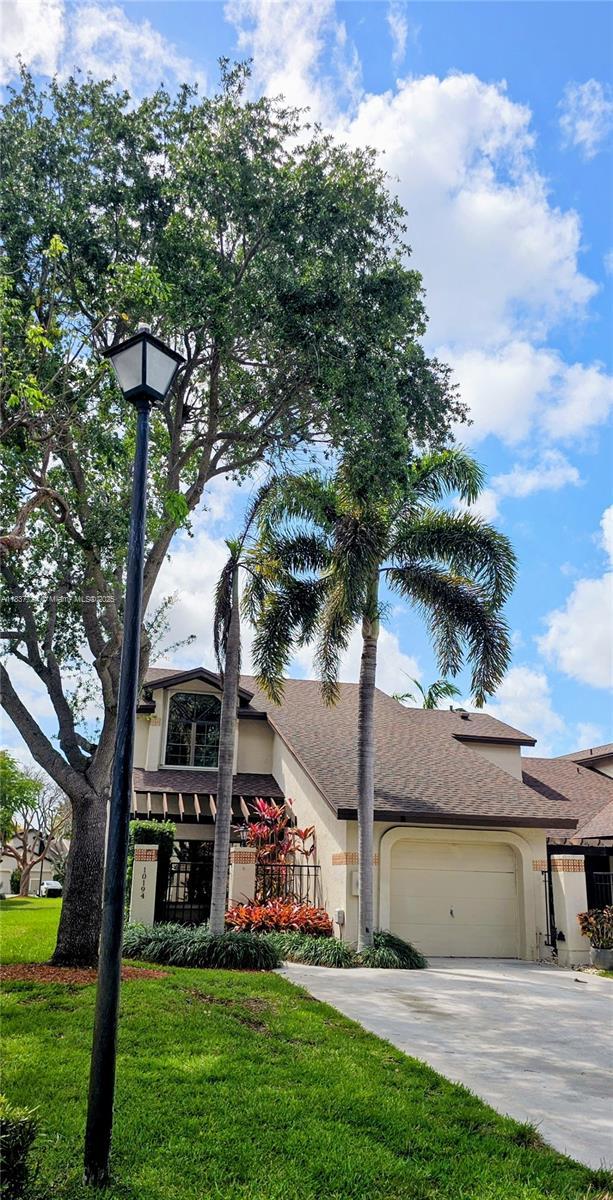 10194 SW 137th Ct Unit 10194, Miami, FL 33186 - view of front of home with an attached garage, driveway, stucco siding, a front lawn, and a shingled roof