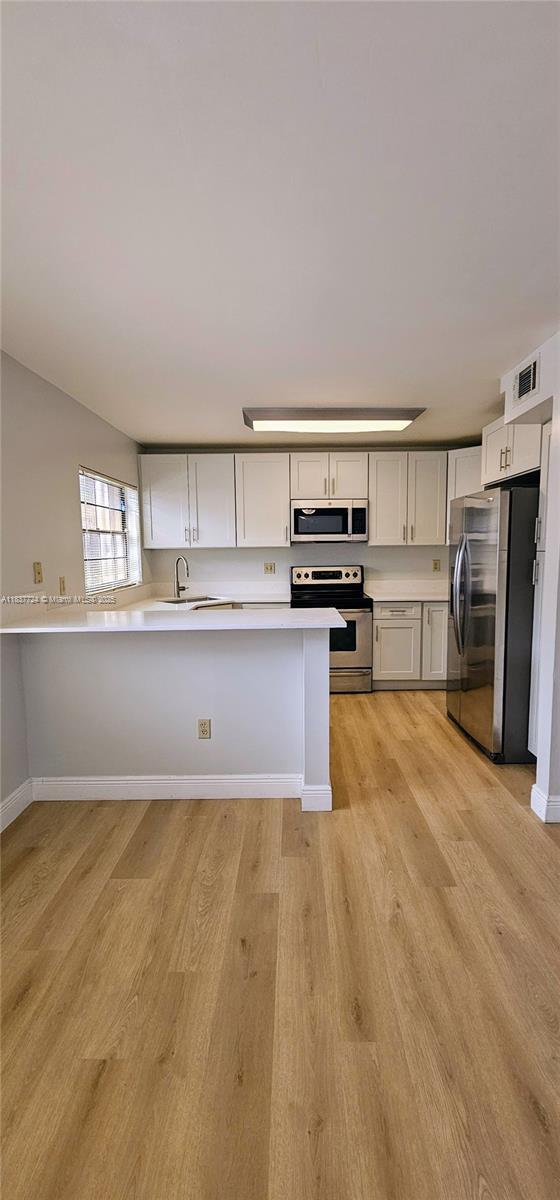 10194 SW 137th Ct Unit 10194, Miami, FL 33186 - kitchen with appliances with stainless steel finishes, light wood-type flooring, light countertops, and a peninsula