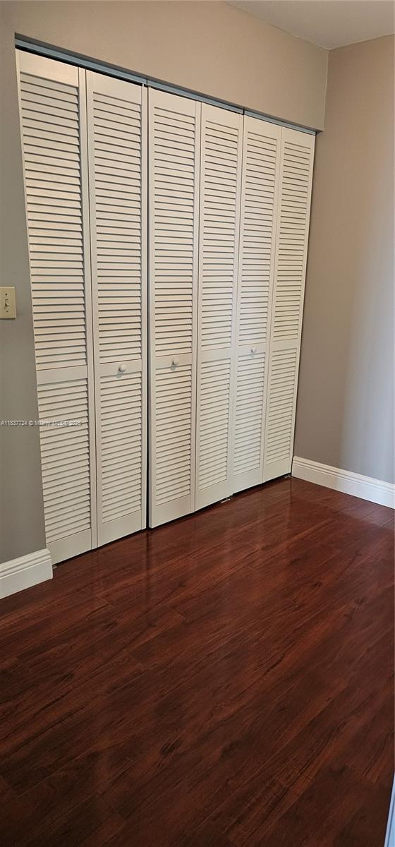 10194 SW 137th Ct Unit 10194, Miami, FL 33186 - unfurnished bedroom featuring dark wood-style flooring and a closet