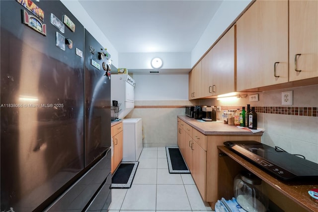 190 E 16th St, Hialeah, FL 33010 - kitchen with stacked washer and clothes dryer, freestanding refrigerator, light tile patterned floors, tile walls, and light brown cabinets