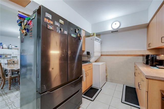 190 E 16th St, Hialeah, FL 33010 - kitchen with stacked washer and clothes dryer, freestanding refrigerator, light countertops, light brown cabinets, and tile walls