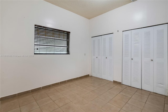 190 E 16th St, Hialeah, FL 33010 - unfurnished bedroom featuring two closets, light tile patterned floors, and a textured ceiling