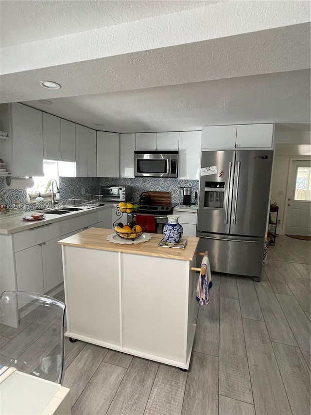 291 NW 95th St, Miami, FL 33150 - kitchen with butcher block counters, appliances with stainless steel finishes, light wood finished floors, white cabinetry, and a textured ceiling