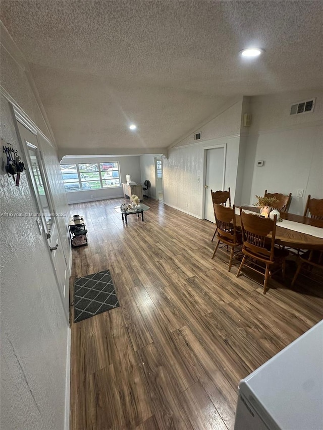 living area featuring lofted ceiling, a textured ceiling, wood finished floors, and recessed lighting