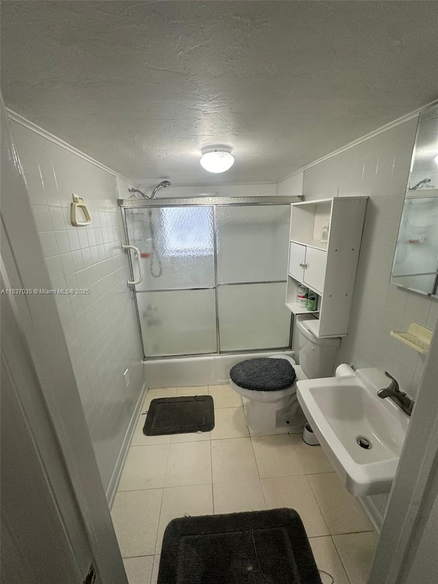 bathroom with a stall shower, a textured ceiling, crown molding, and tile patterned flooring