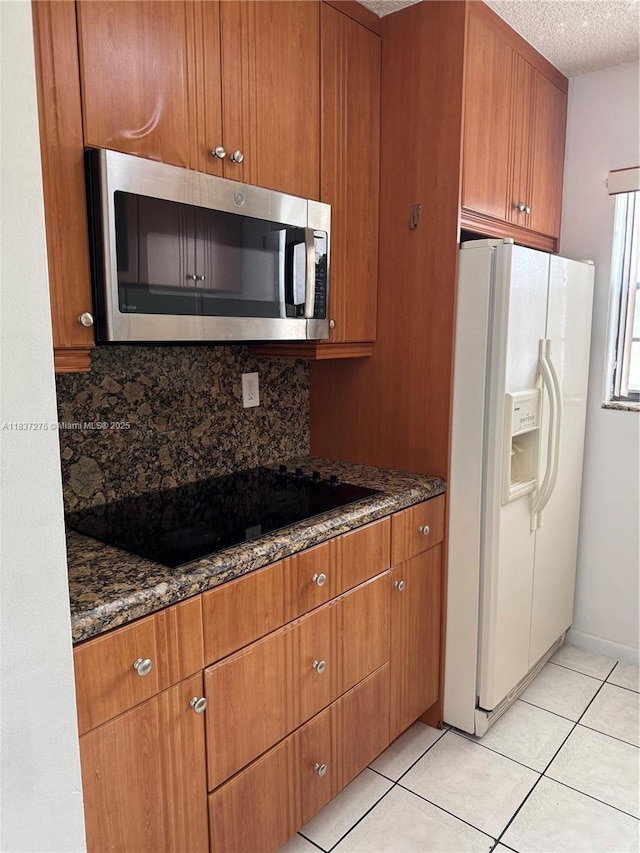 18240 Mediterranean Blvd Unit 5-11, Hialeah, FL 33015 - kitchen featuring stainless steel microwave, white refrigerator with ice dispenser, black electric cooktop, decorative backsplash, and a textured ceiling