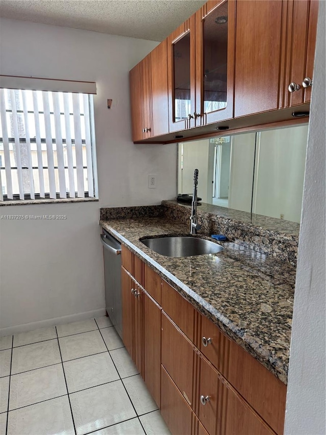 18240 Mediterranean Blvd Unit 5-11, Hialeah, FL 33015 - kitchen featuring dishwasher, dark stone counters, light tile patterned floors, glass insert cabinets, and brown cabinetry