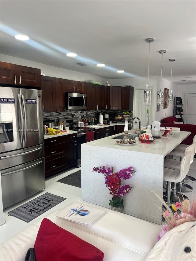 11925 SW 6th St, Miami, FL 33184 - kitchen featuring appliances with stainless steel finishes, light countertops, decorative backsplash, a breakfast bar area, and hanging light fixtures