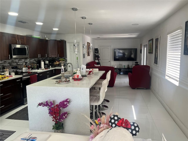 11925 SW 6th St, Miami, FL 33184 - kitchen featuring appliances with stainless steel finishes, a kitchen bar, light countertops, open floor plan, and decorative backsplash
