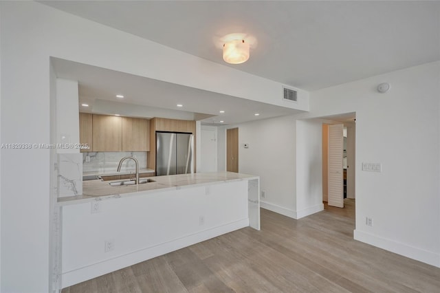 5600 Collins Ave Unit 10L, Miami Beach, FL 33140 - kitchen featuring freestanding refrigerator, a peninsula, light wood-style flooring, light stone countertops, and tasteful backsplash