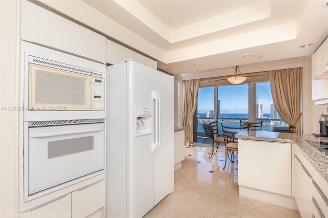 7000 Island Blvd Unit 2504, Aventura, FL 33160 - kitchen with white appliances, a tray ceiling, white cabinets, and light tile patterned flooring