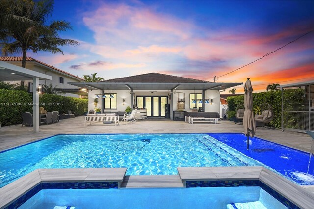 8236 SW 36th St, Miami, FL 33155 - pool at dusk featuring french doors, an outdoor living space, an outdoor structure, an exterior structure, and a pool with connected hot tub