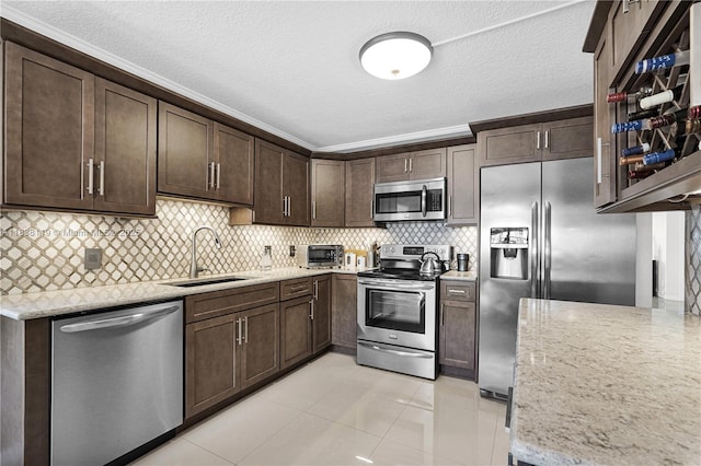 12650 SW 6th St Unit 101K, Pembroke Pines, FL 33027 - kitchen with appliances with stainless steel finishes, dark brown cabinets, decorative backsplash, light stone countertops, and light tile patterned floors