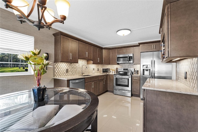 12650 SW 6th St Unit 101K, Pembroke Pines, FL 33027 - kitchen with appliances with stainless steel finishes, tasteful backsplash, light stone counters, a chandelier, and dark brown cabinets