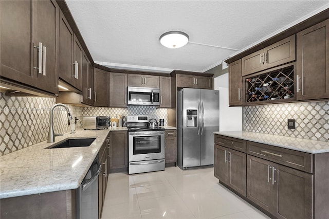 12650 SW 6th St Unit 101K, Pembroke Pines, FL 33027 - kitchen with appliances with stainless steel finishes, tasteful backsplash, dark brown cabinets, light stone countertops, and light tile patterned flooring