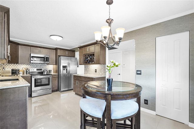 12650 SW 6th St Unit 101K, Pembroke Pines, FL 33027 - kitchen with stainless steel appliances, crown molding, dark brown cabinetry, light tile patterned flooring, and a chandelier