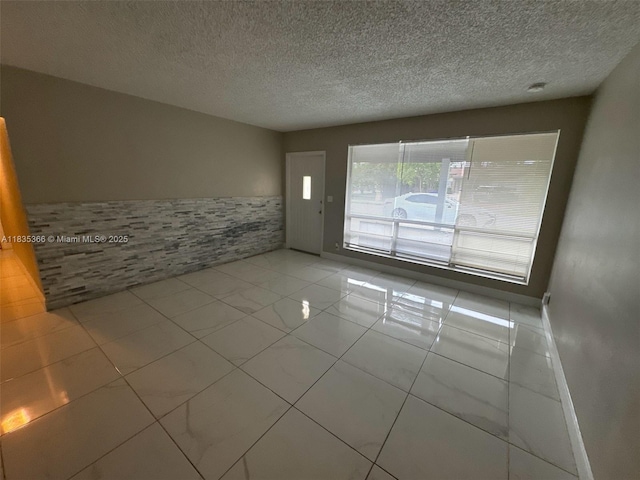 2307 Rodman St, Hollywood, FL 33020 - spare room featuring a textured ceiling and a wainscoted wall