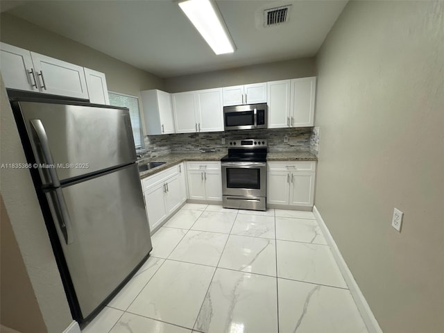 2307 Rodman St, Hollywood, FL 33020 - kitchen with stainless steel appliances, light marble finish flooring, white cabinets, and backsplash